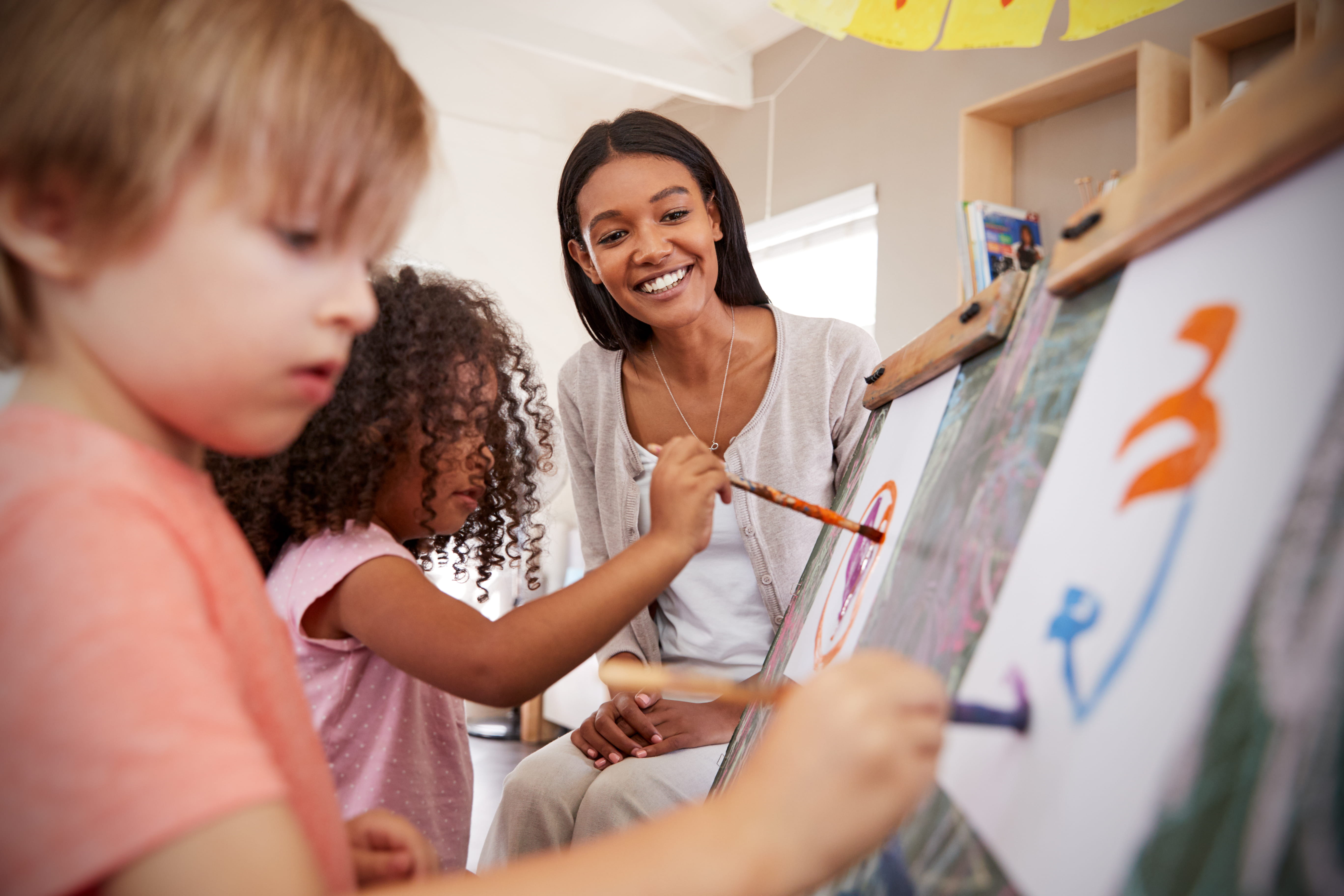 Teacher At Montessori School Helping Children in Art Class