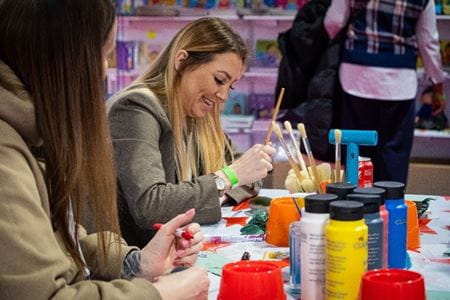 Lady smiling whilst painting a pebble rock at the activity zone at the Childcare and Education Expo 
