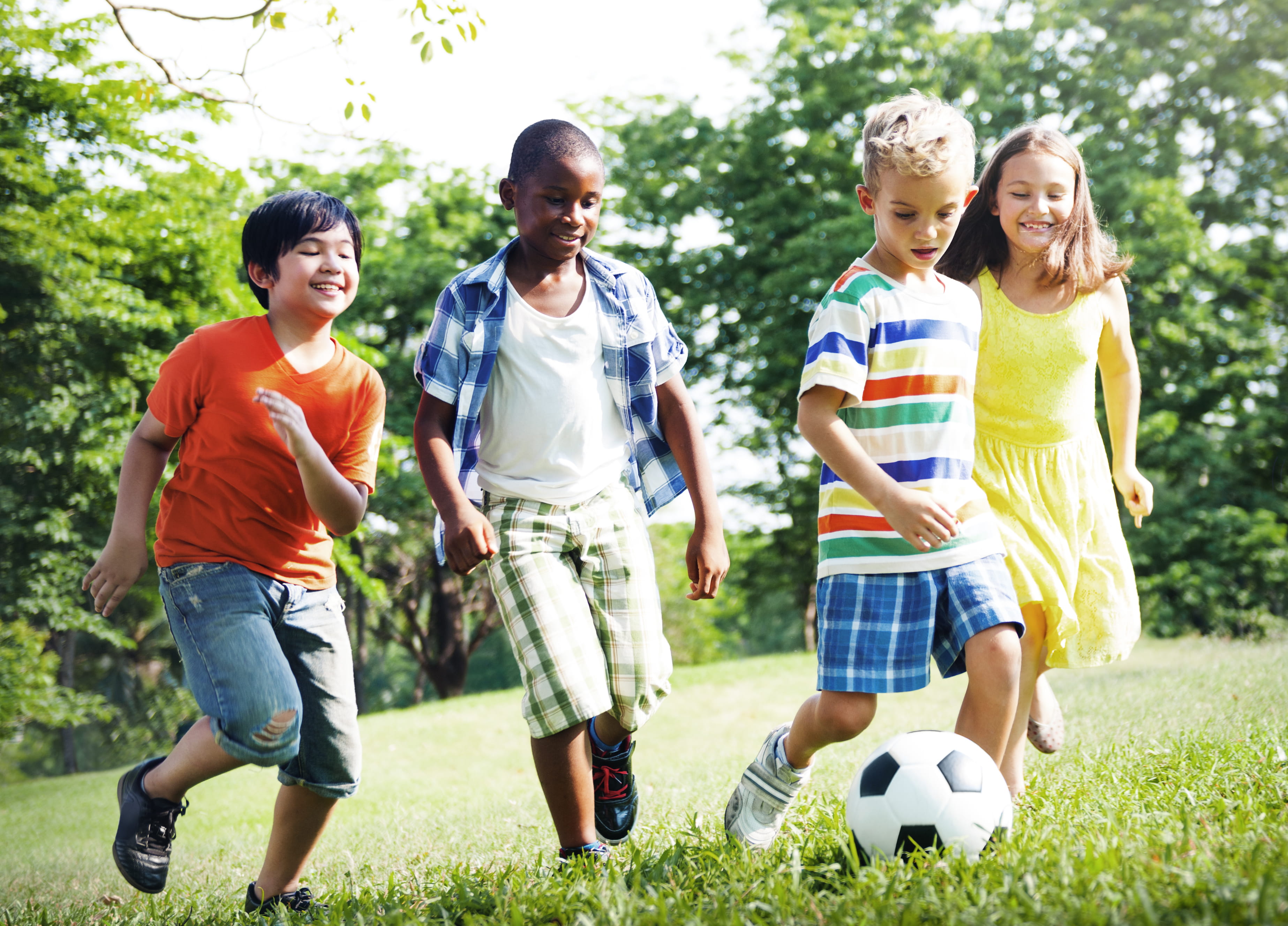 Group of smiley young children playing football together