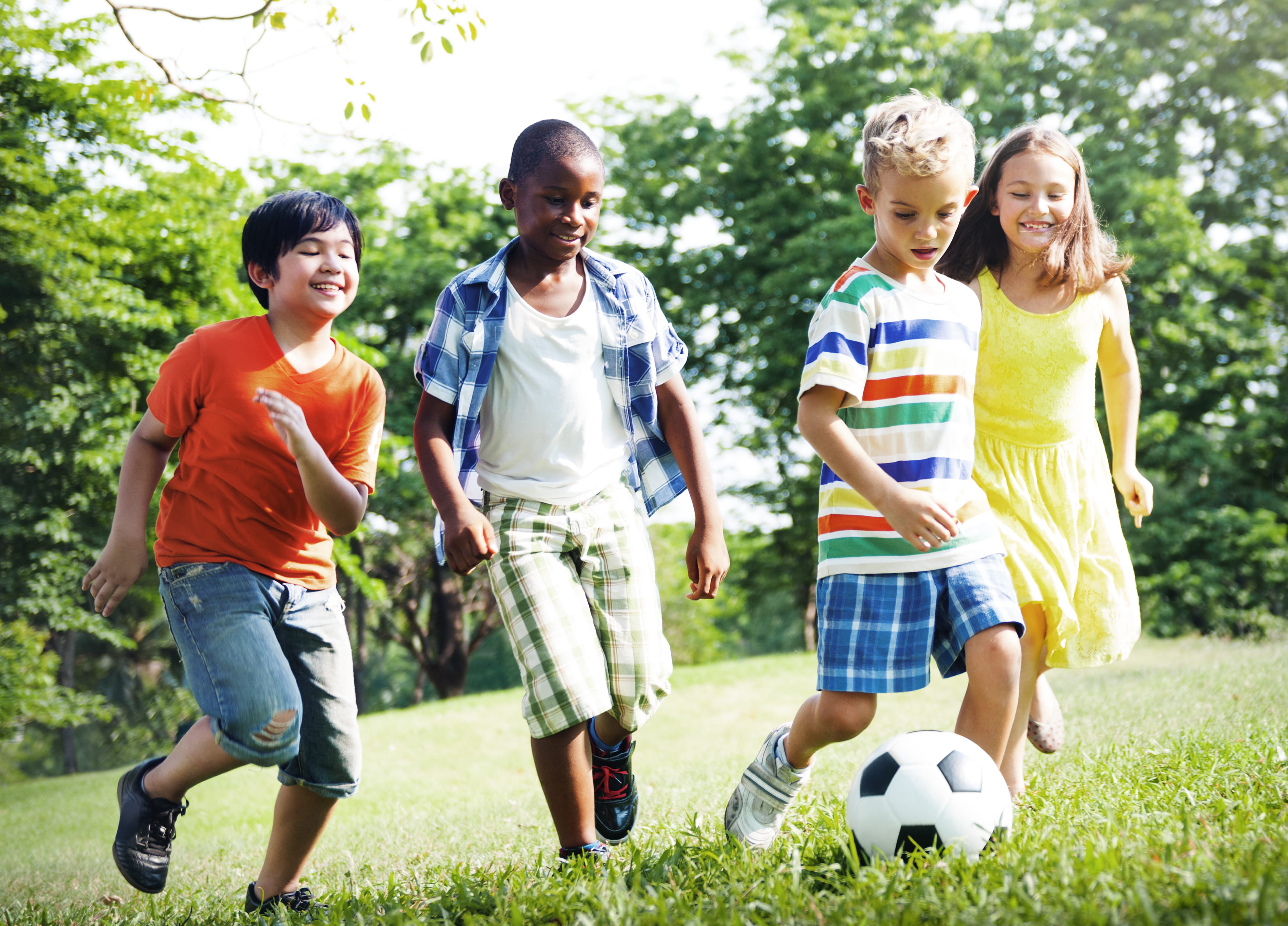 Group of smiley young children playing football together 