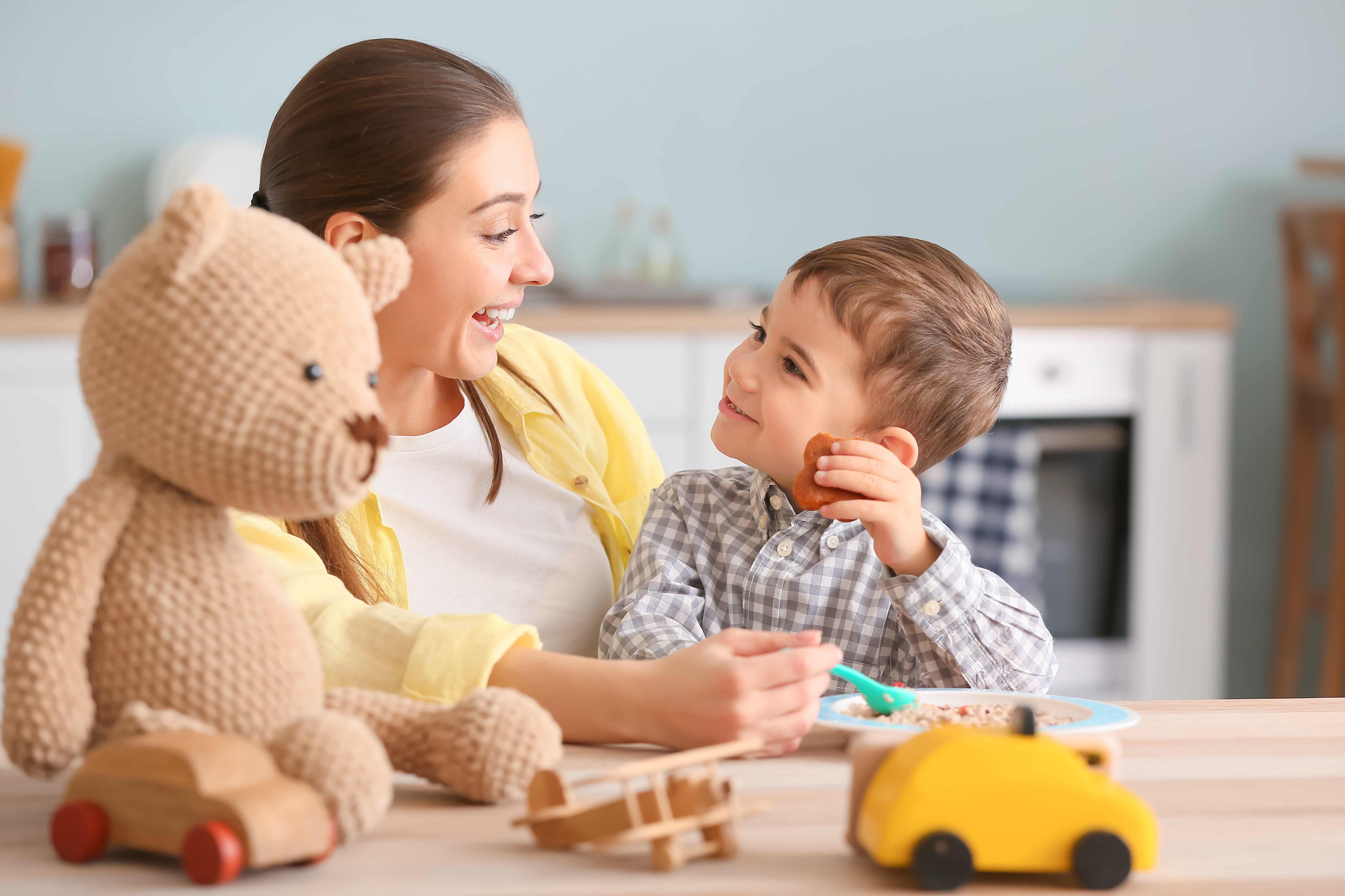 Childminder feeding little boy in kitchen