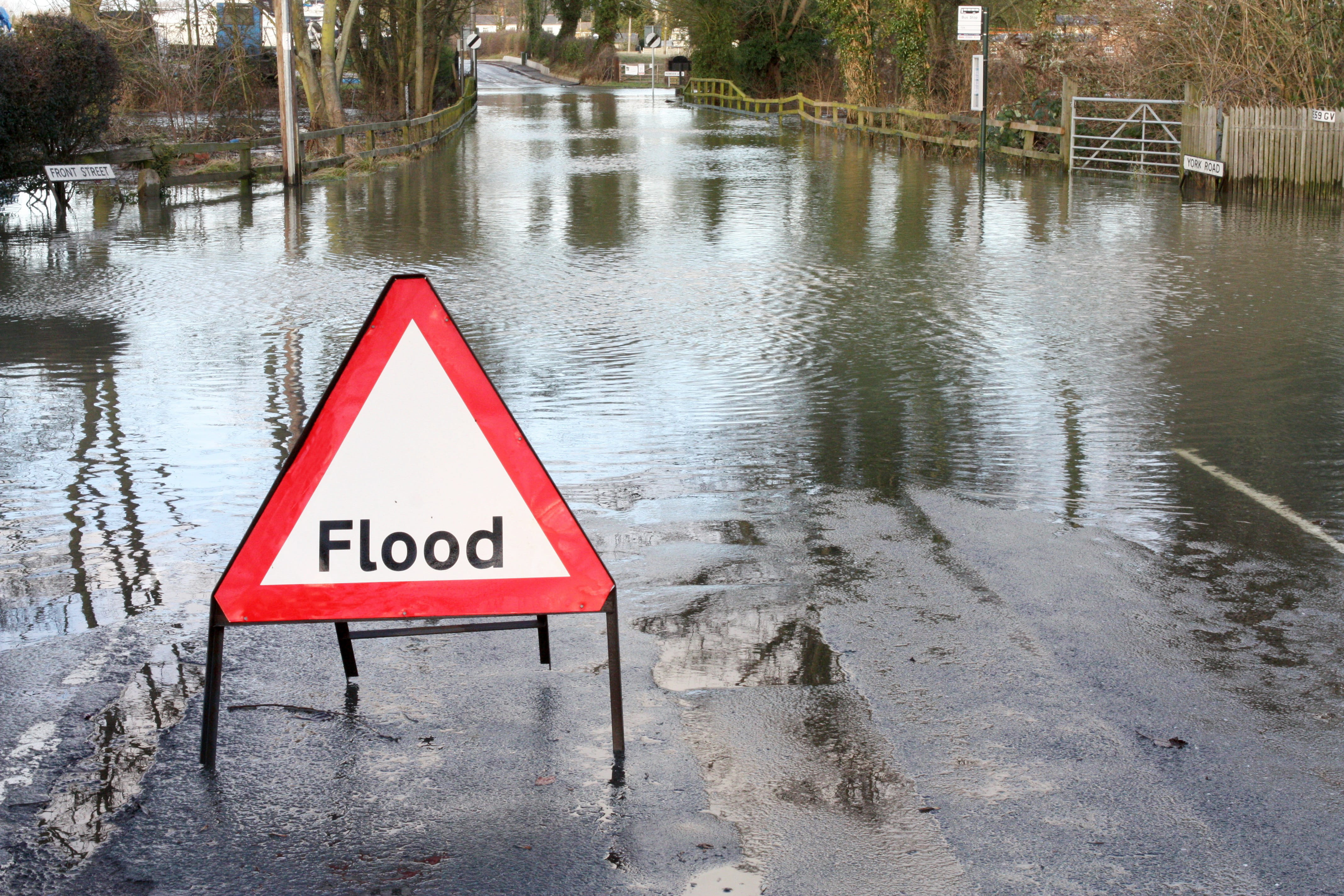 Road closed because of flooding with white and red flood road sign