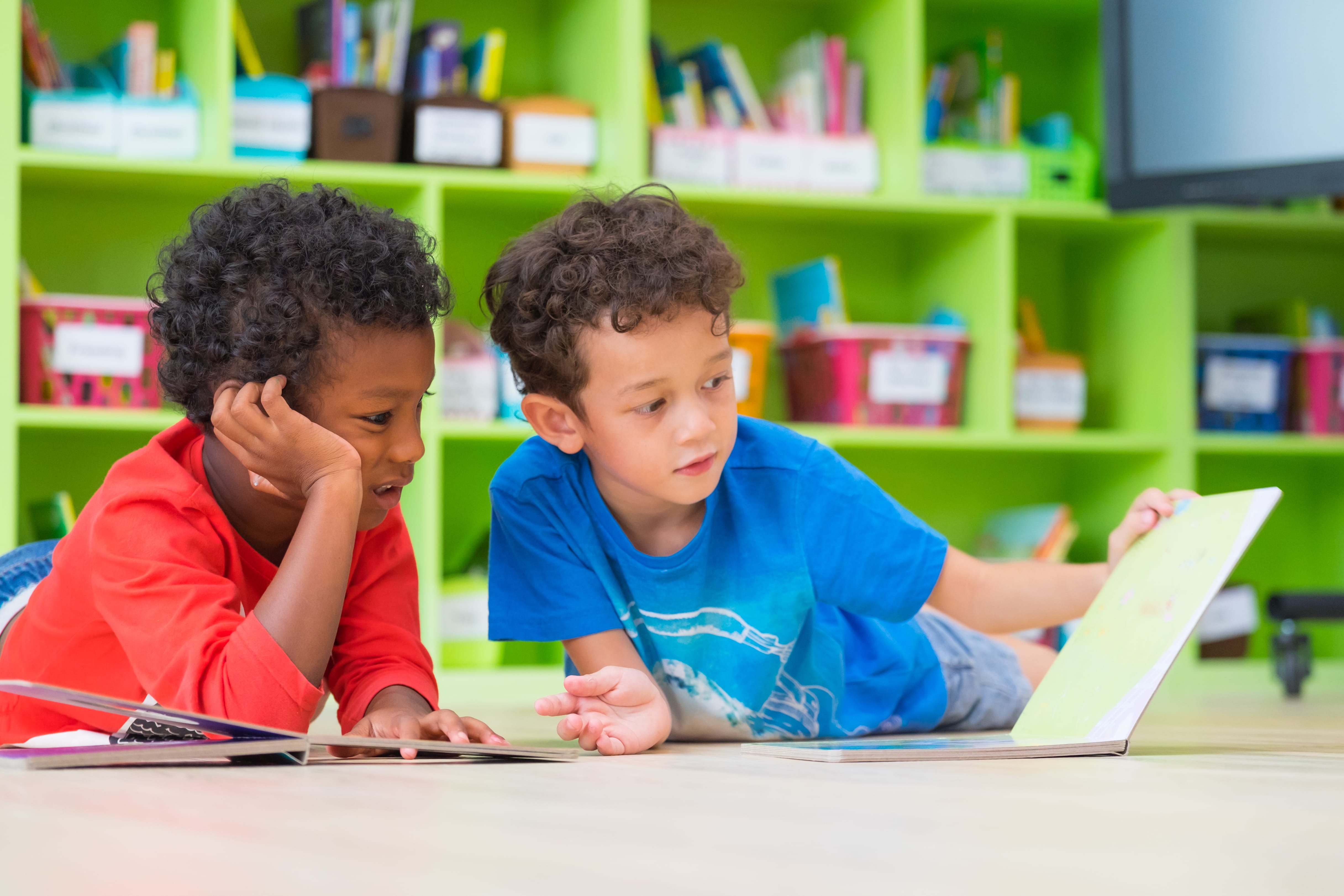 Two preschool children boys reading a book together in classroom