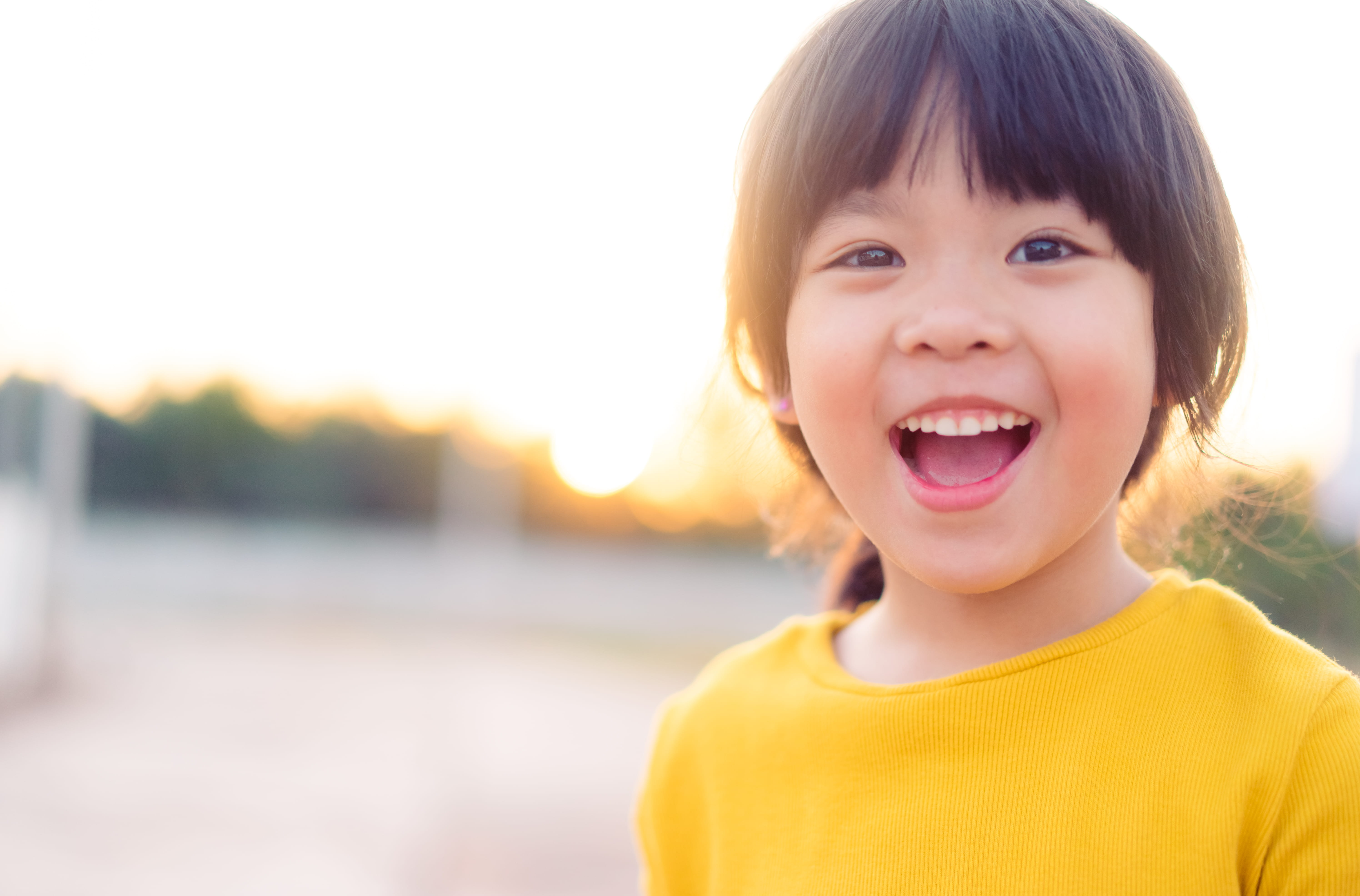 Happy little girl showing front teeth with big smile and laughing