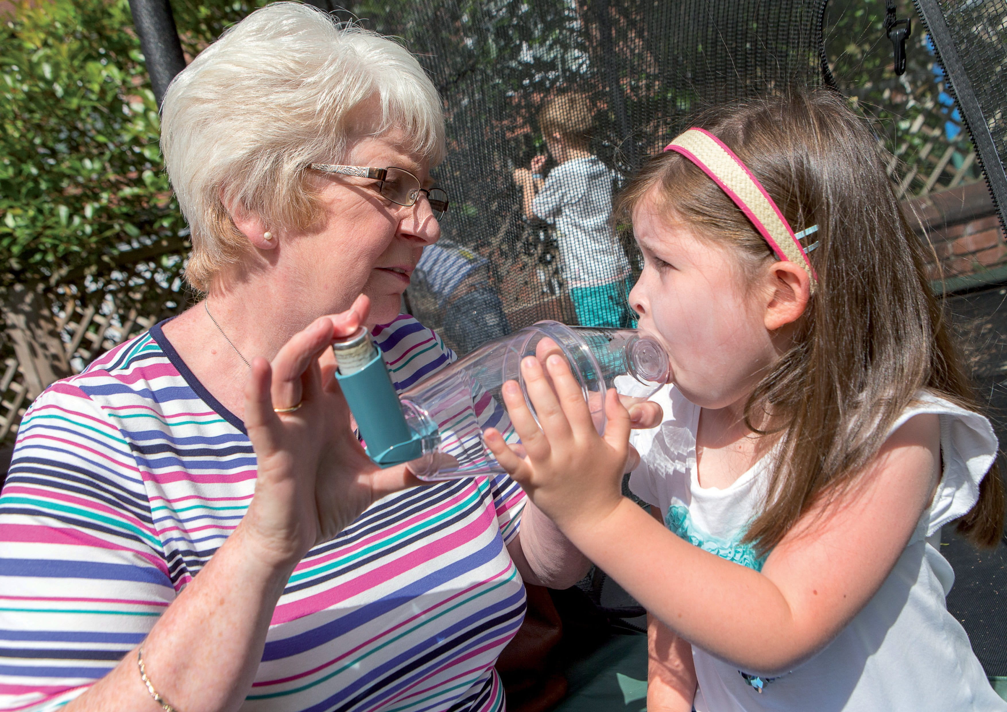 Someone helping a child who is having an asthma attack take their inhaler