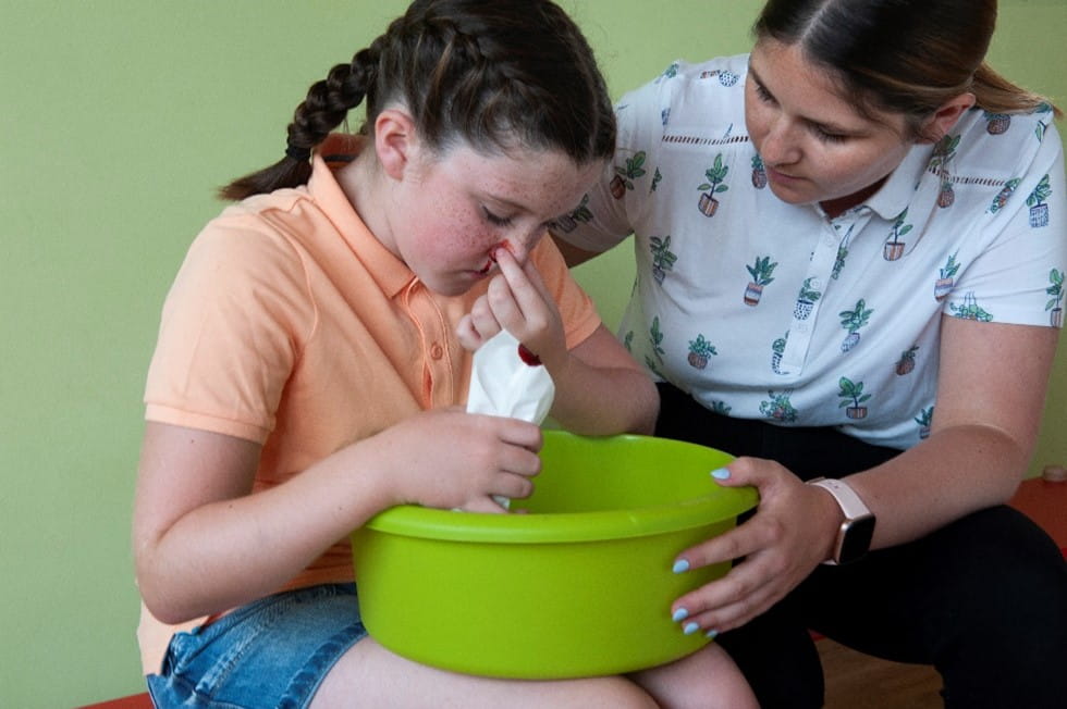Adult helping child with nosebleed