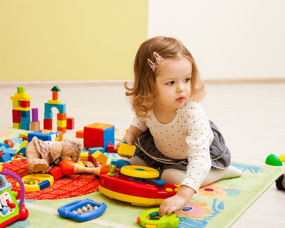 Toddler playing with colourful toys on play mat