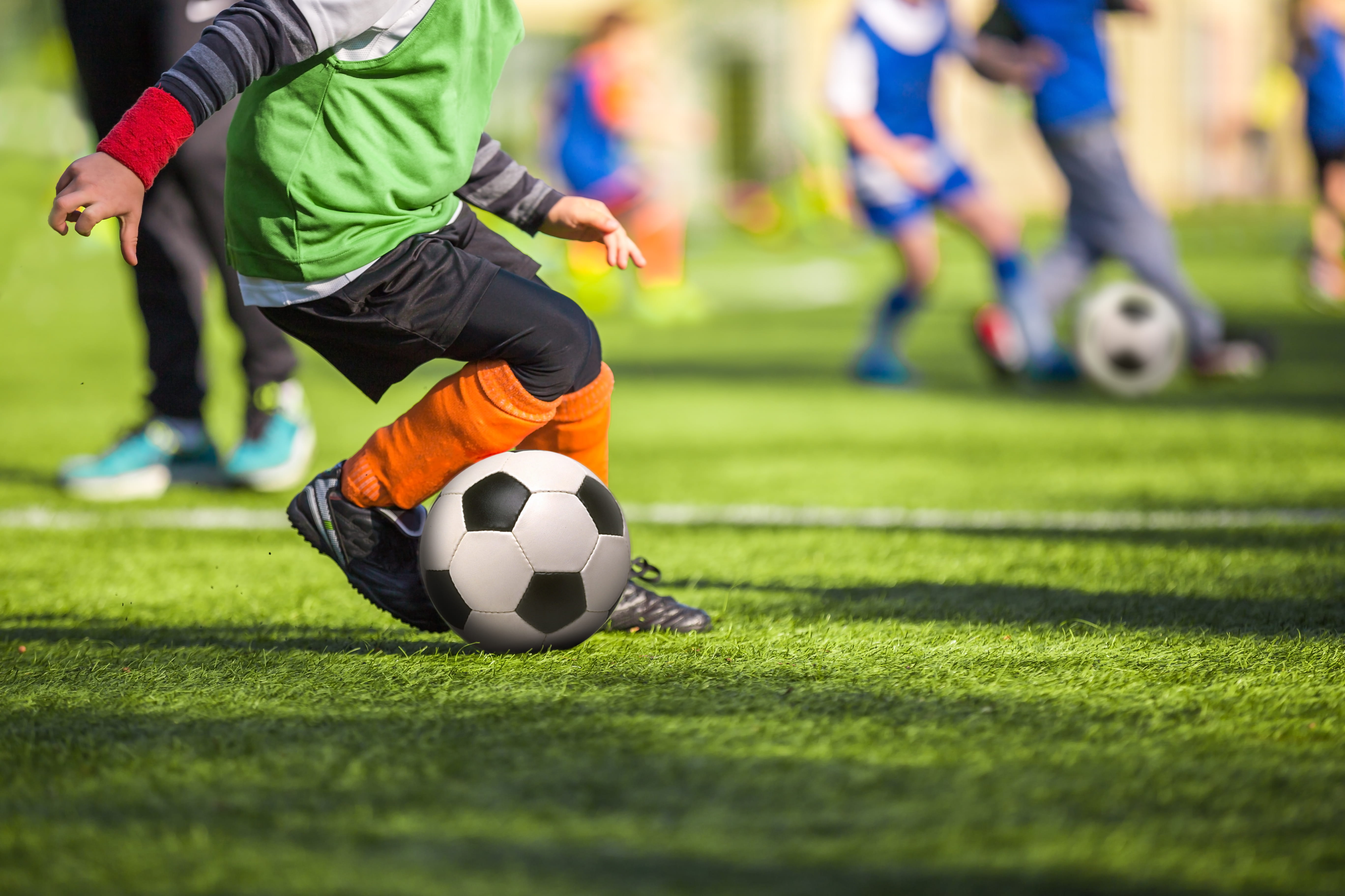 Close up of child with ball at feet at football training match