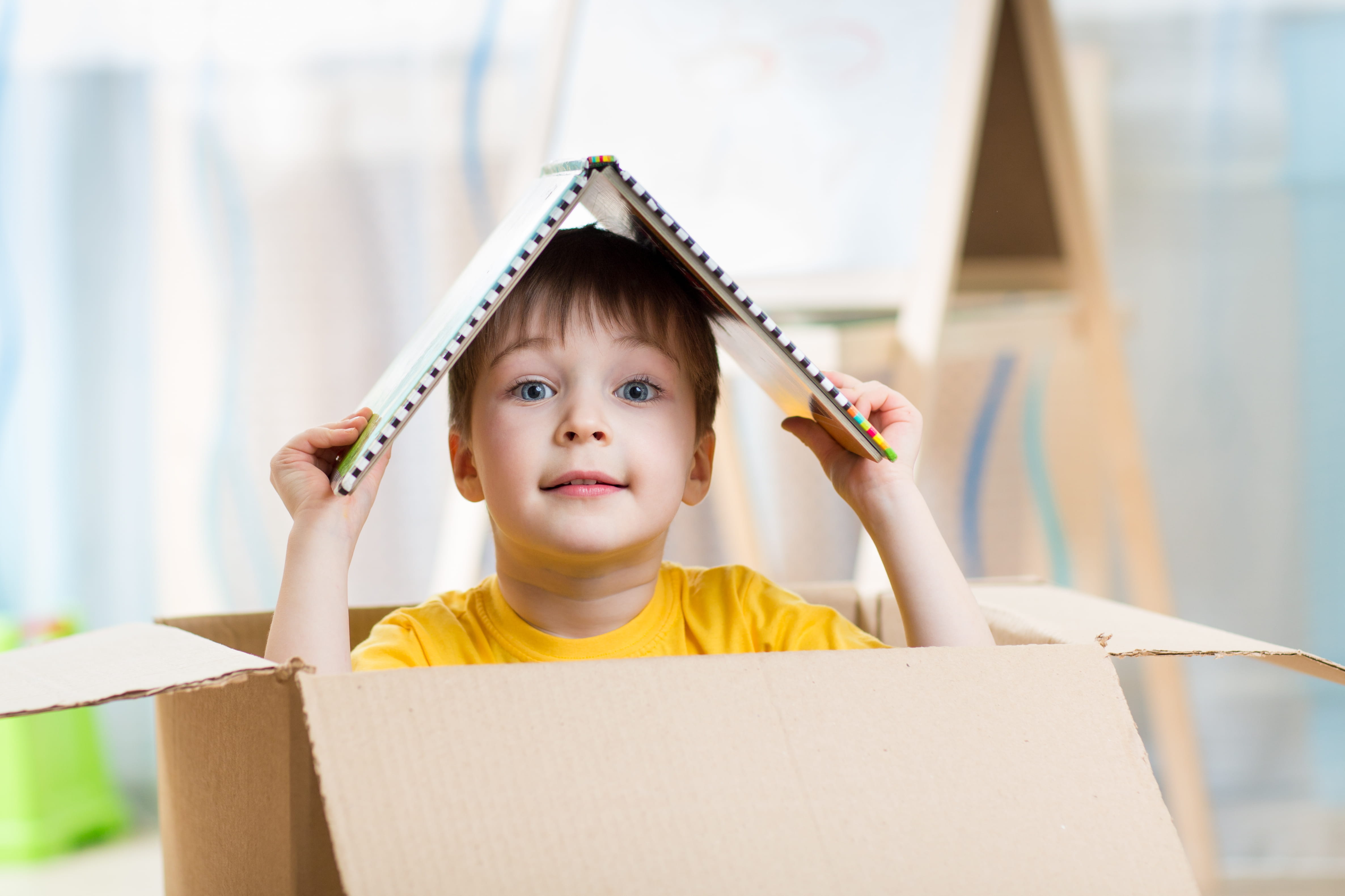 Kid boy playing in a toy house in children room