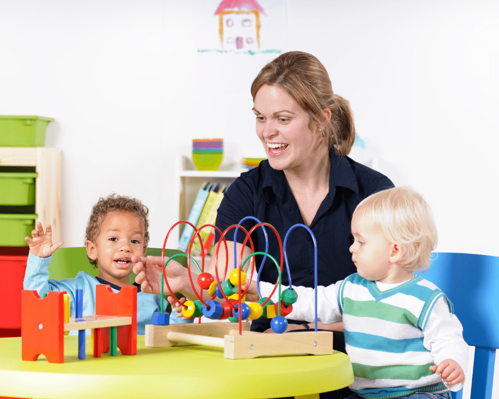 Toddlers enjoying playtime with childminder / nursery school teacher