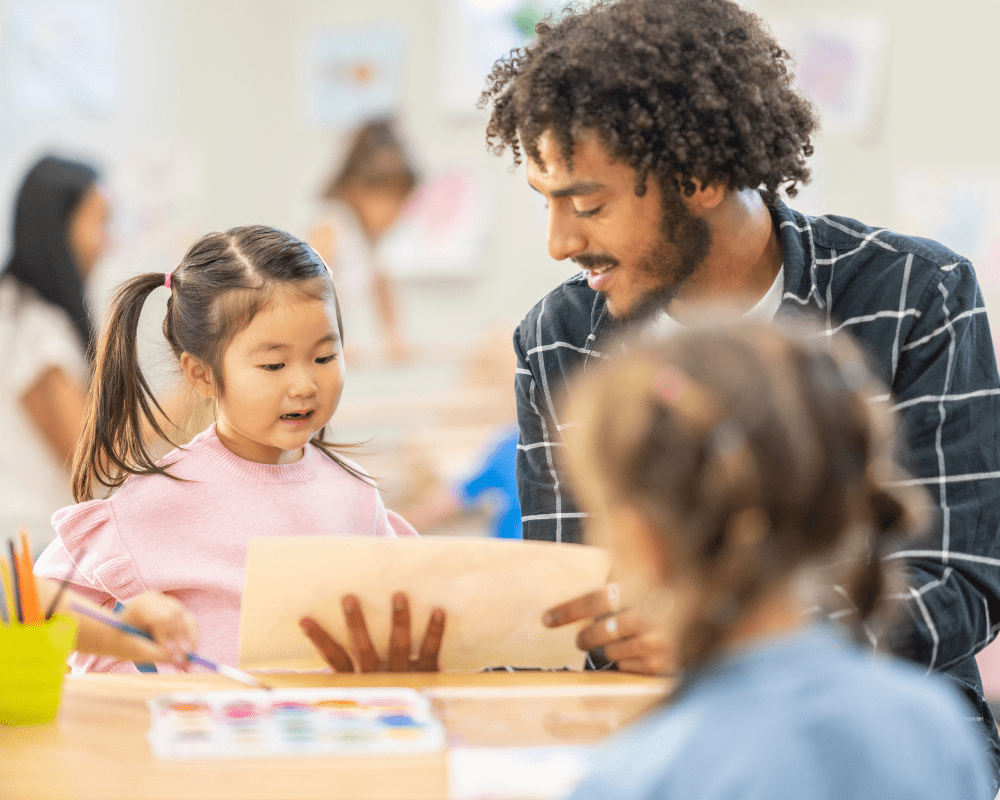 Childcare professional working with young child on an art project