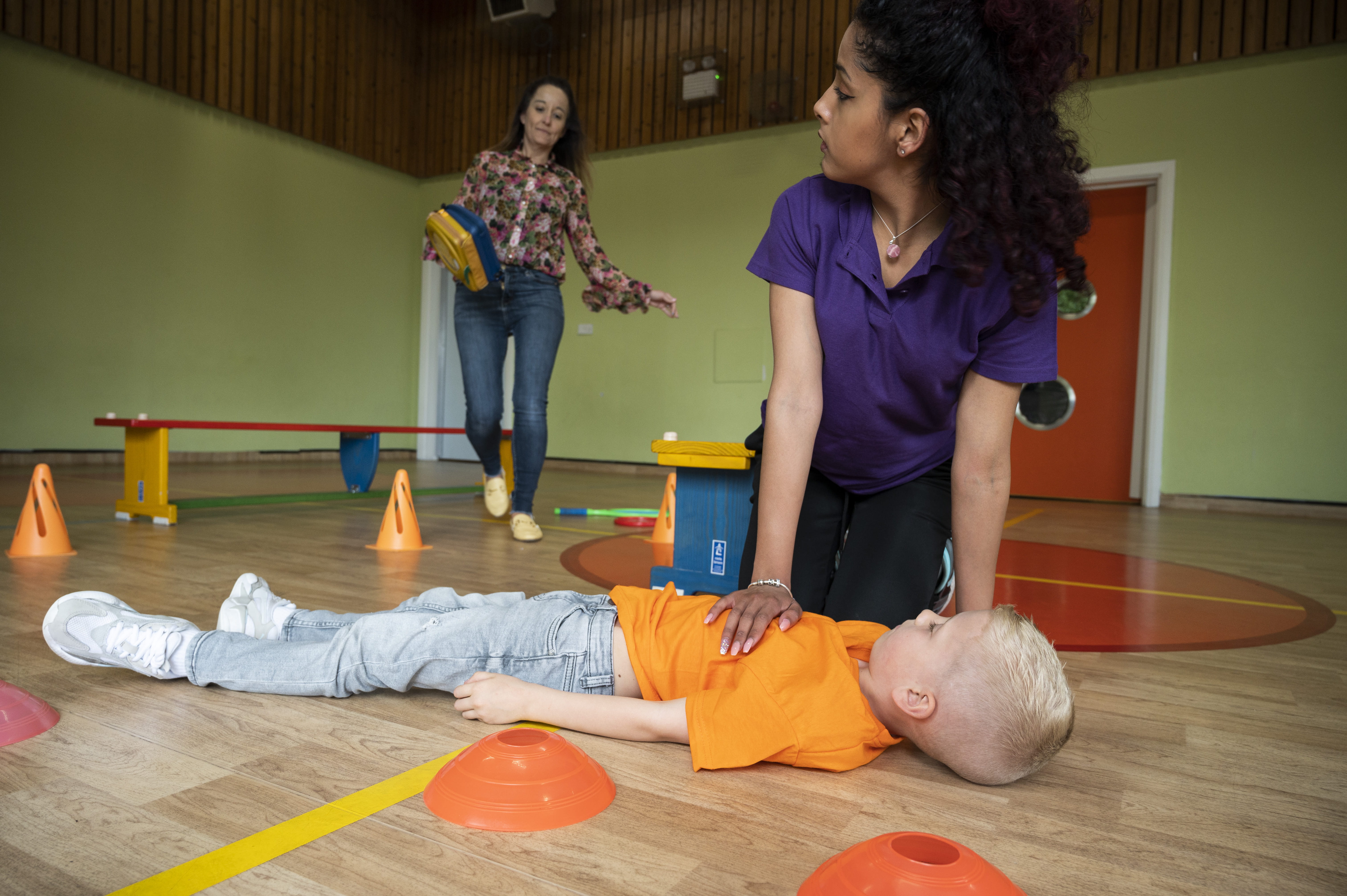 First aider attending to child on floor in sports hall