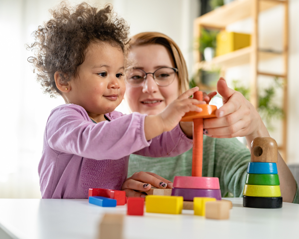 Mother or childcarer with toddler playing with a colourful and educational didactic toy