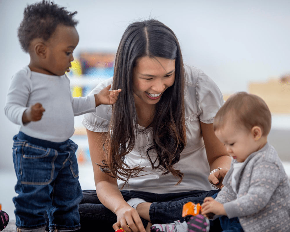 Childcare provider interacting and playing with toddlers at day care