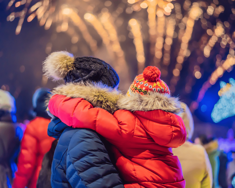 Parent carrying child as they watch a firework display