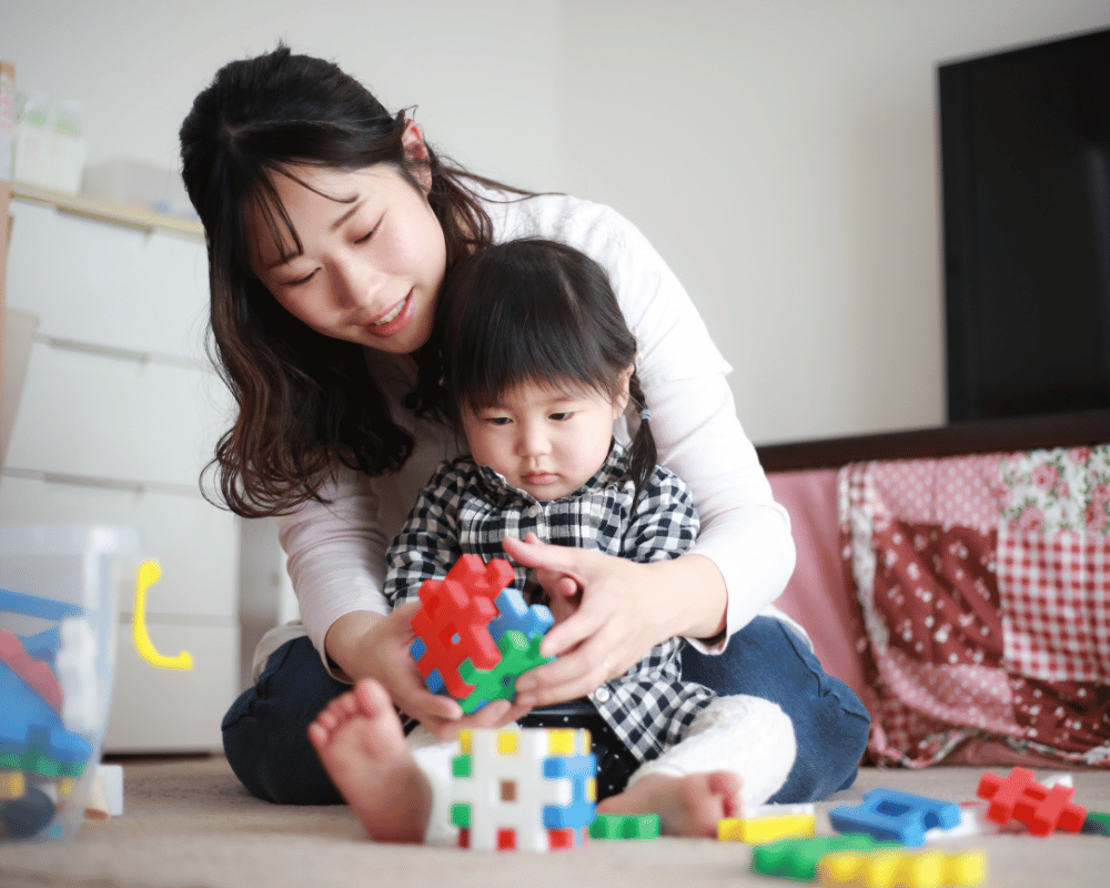 Parent and toddler playing at home with colourful toys