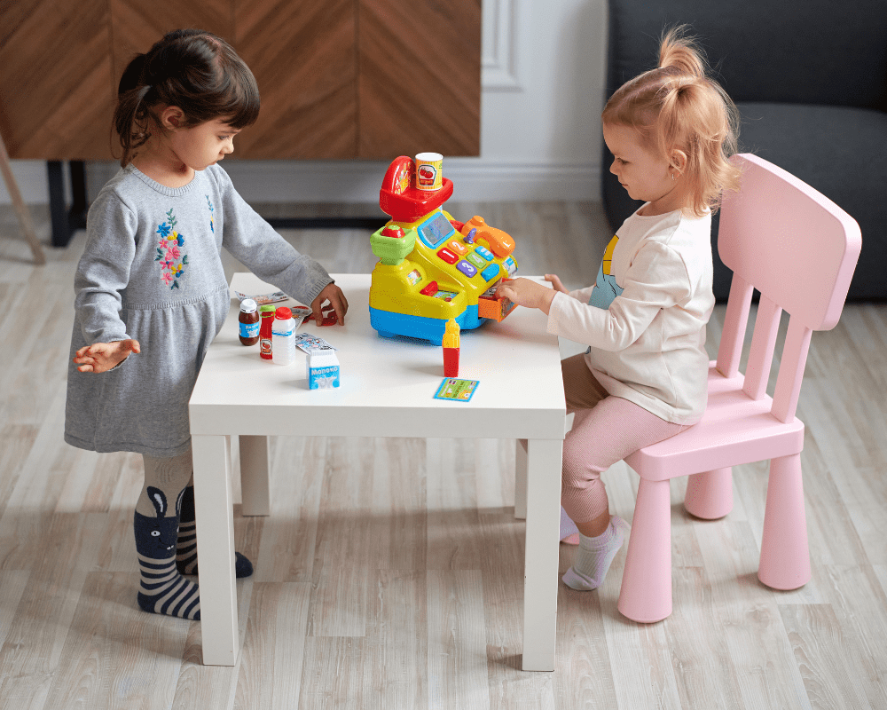 Two children playing together with toy till and accessories 