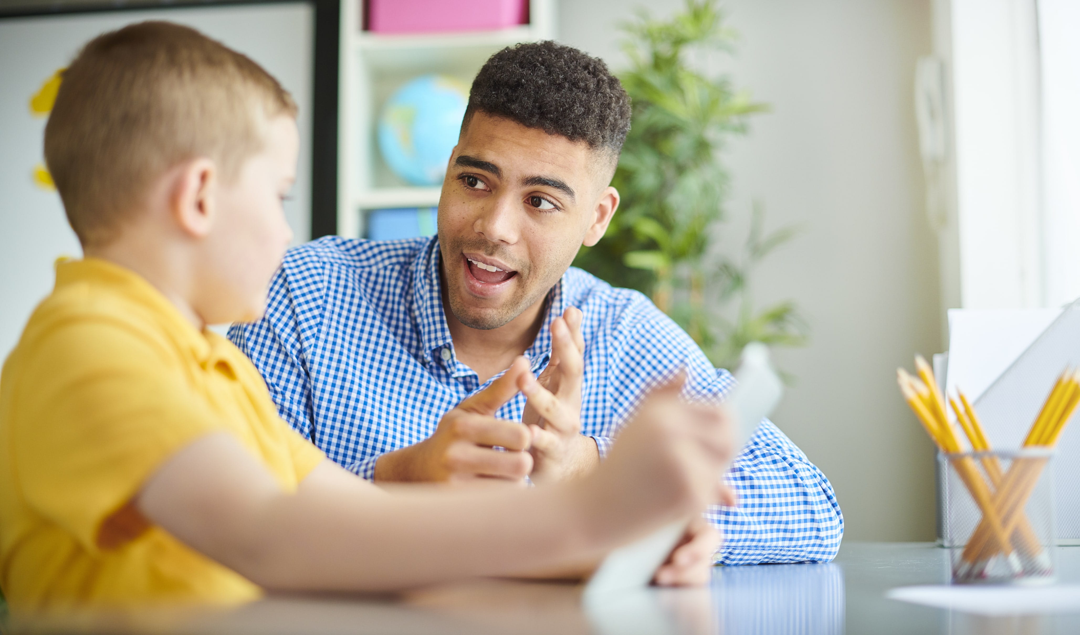 A young male tutor teacher is helping one of his students learn how to count