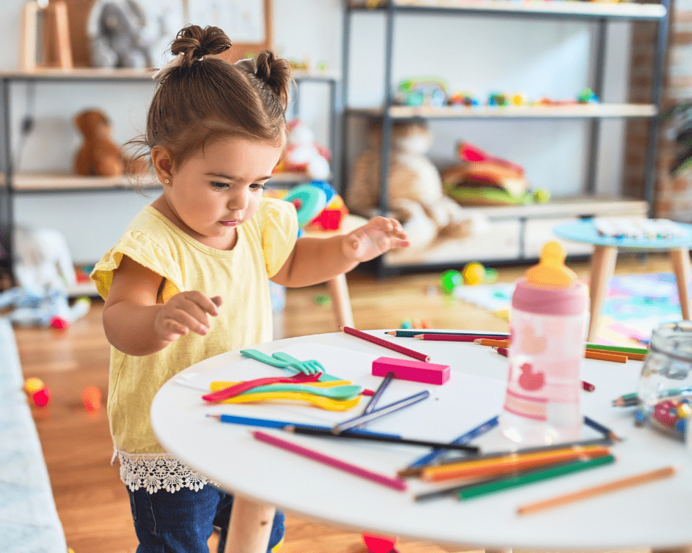 Toddler standing playing with toys on the table at kindergarten