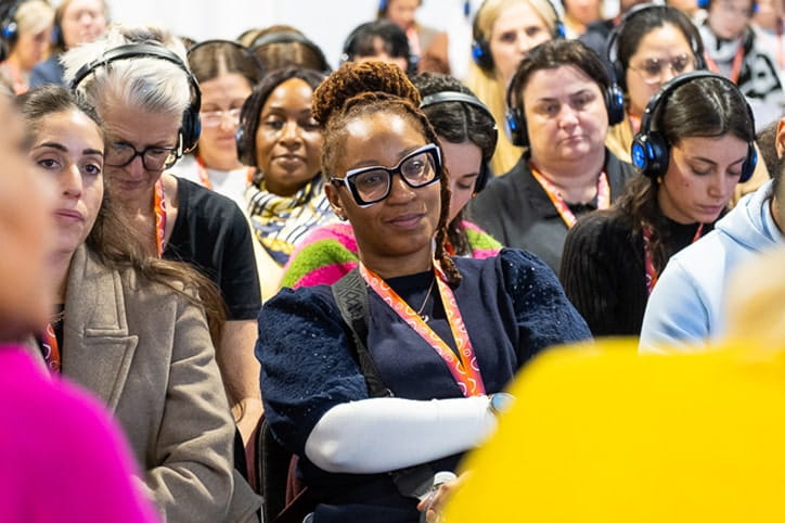 Female audience member wearing glasses watches on as a panel discuss childcare matters at the childcare expo
