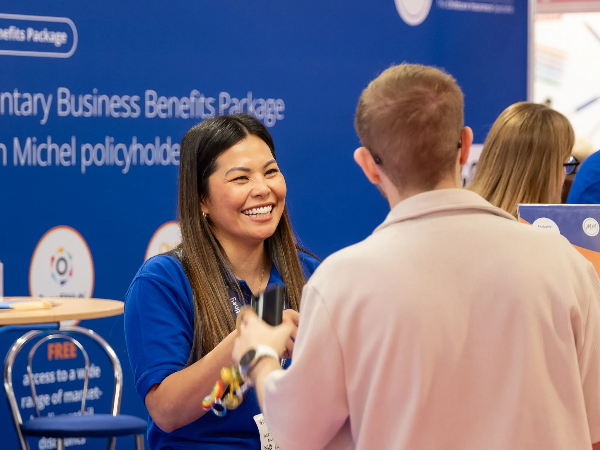 Woman smiling and speaking to man on Morton Michel insurance stand at Childcare & Education Expo 