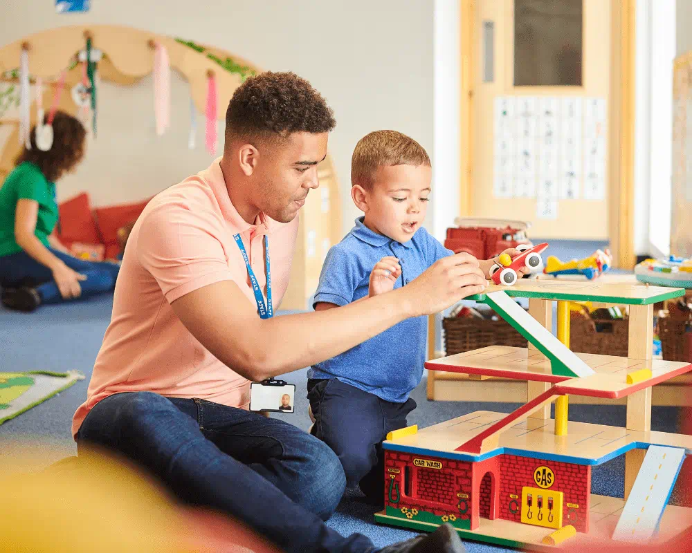 Nursery school teacher playing toys with child in classroom