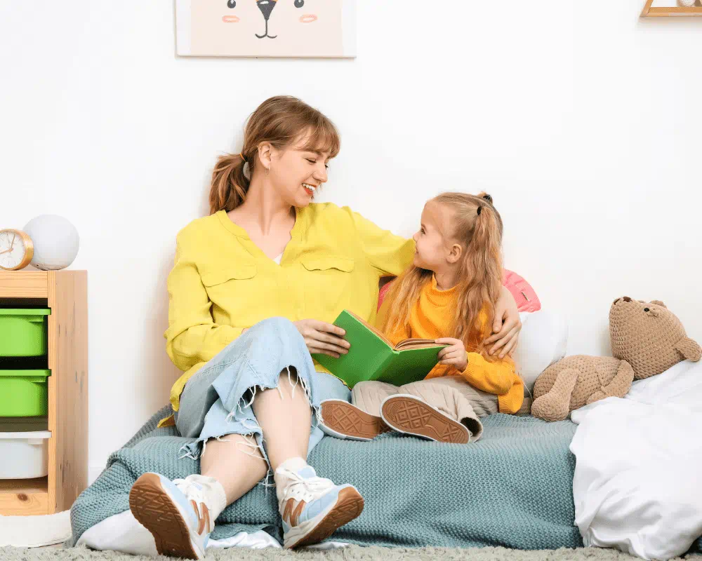 Childcare provider with a little girl reading a book in bedroom 
