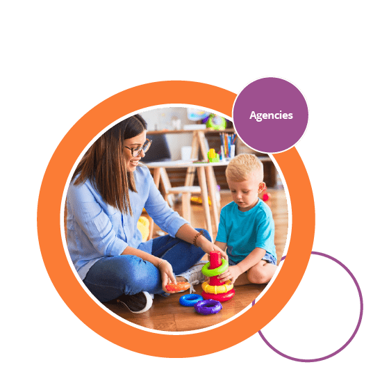Roundel image showing childcare provider playing with young child on the floor in a preschool or nursery classroom with colourful toys