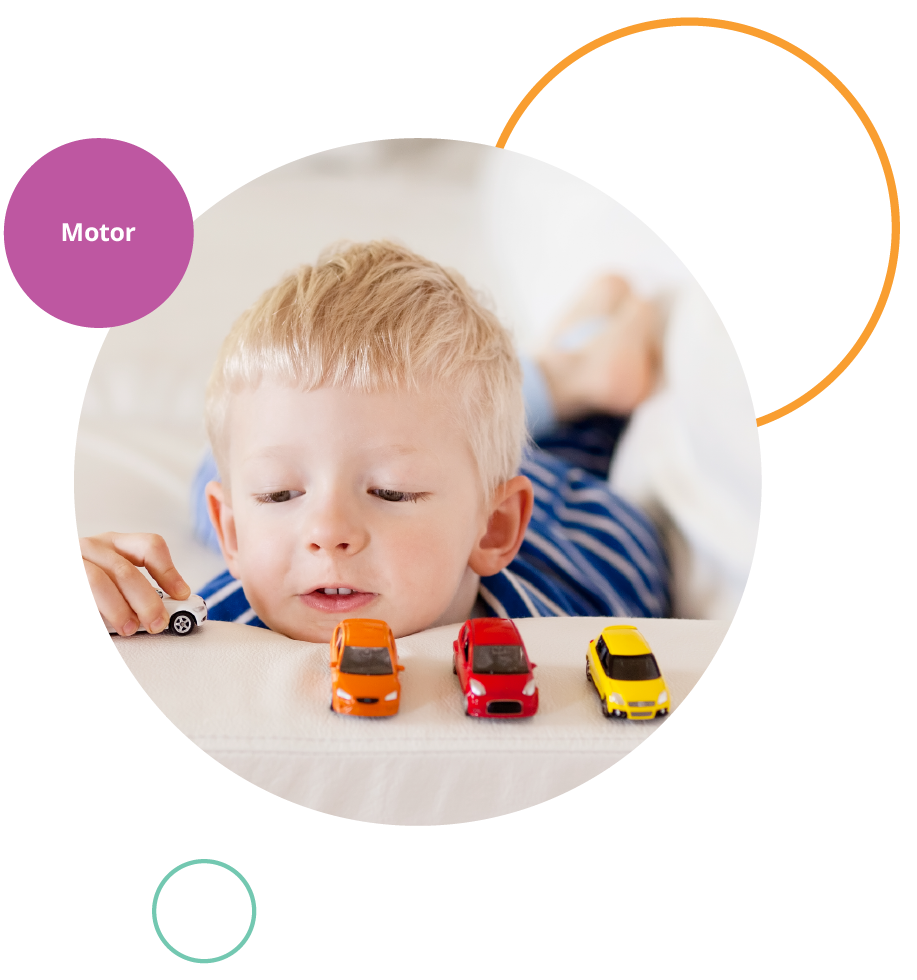 Little boy lying on sofa with legs crossed playing with toy cars