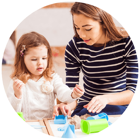 Young girl child with nursery or preschool teacher making sand shapes
