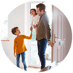 Father standing by open front door in hallway with children