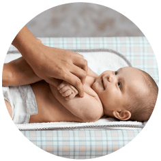 Smiling baby lying on mat with close up of hands massaging baby
