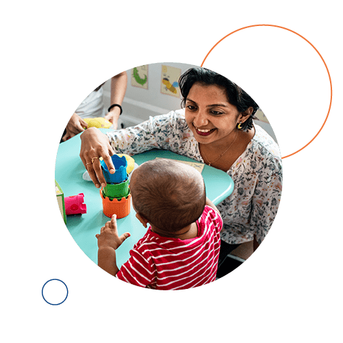 Woman and young child playing with colourful blocks at nursery