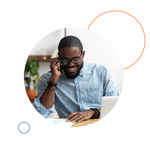 Smiling man talking on phone in front of laptop