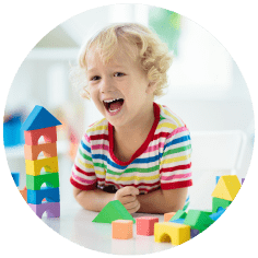 A child smiling and playing with brightly coloured blocks.