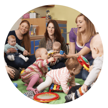 A group of parents and children playing together in a community room.