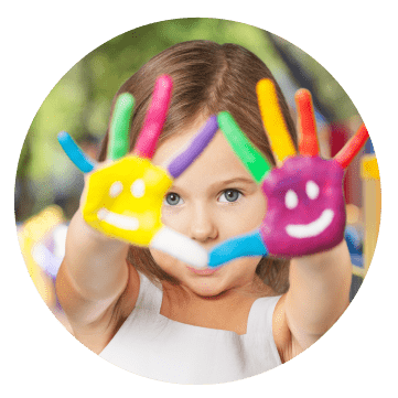 A girl raising her hands to the camera, which are covered in bright paint.