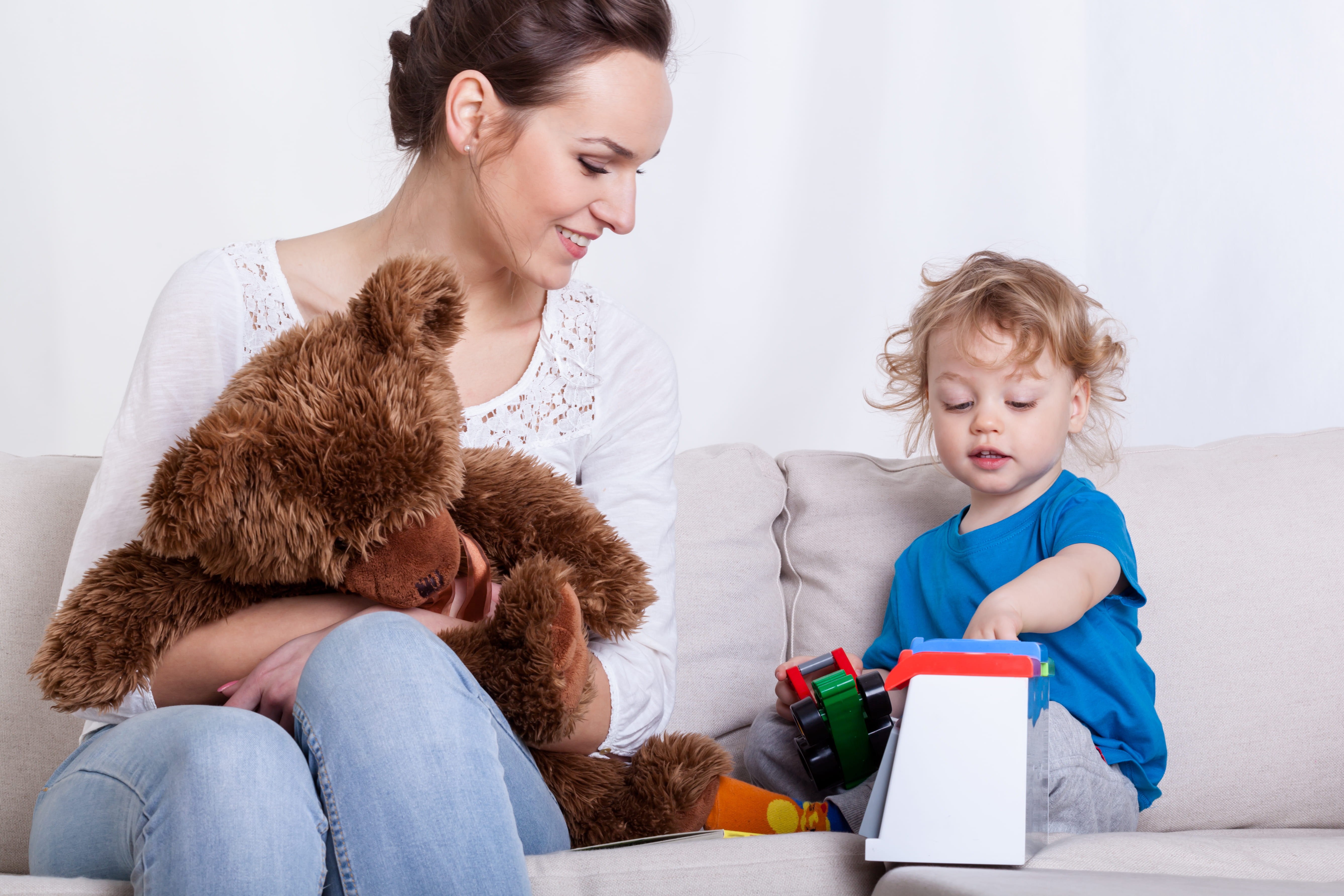 Childminder holding little boy in home, smiling  