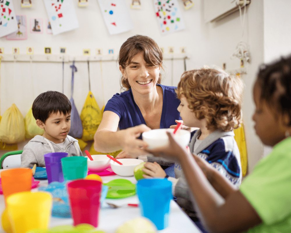 Teacher with preschool kids at desk during lunch