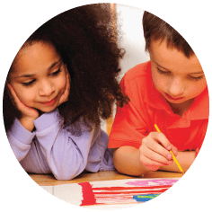 One child painting using a brush whilst the child next to him looks on.