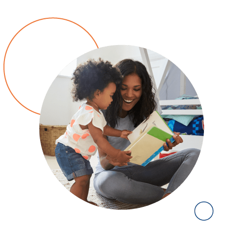 Smiling mother reading book to little daughter